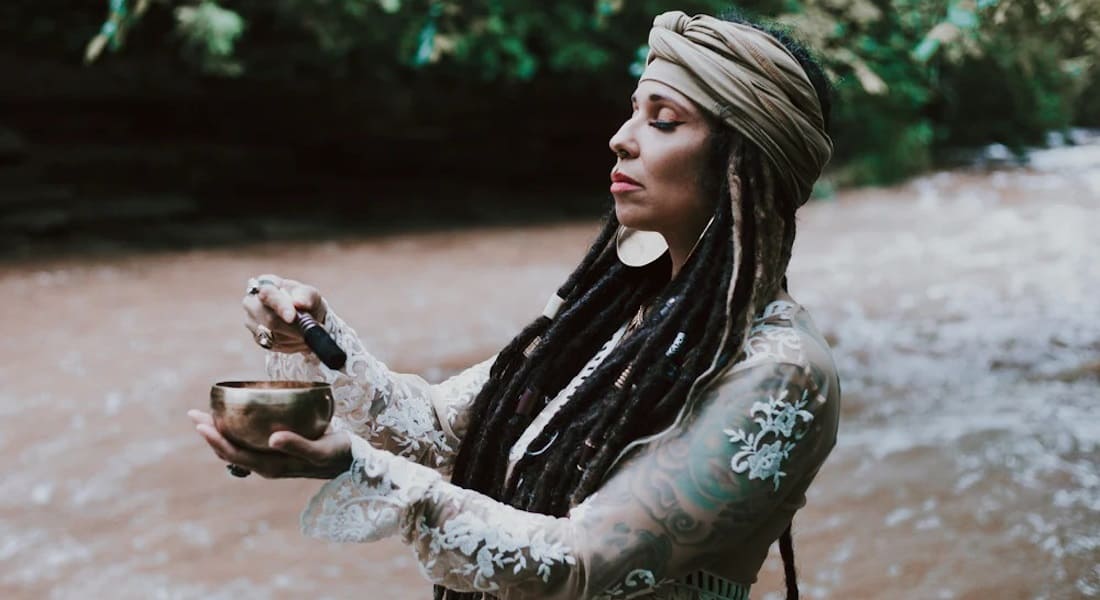 Une femme à proximité d'une rivière qui joue avec un Bol Tibétain