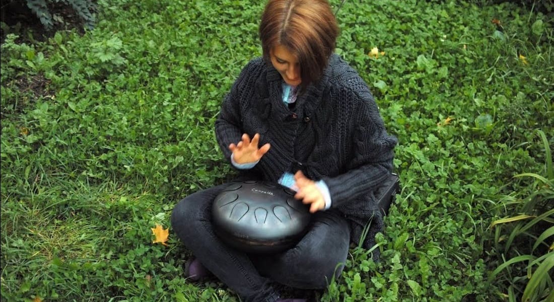 Une femme assise dans l'herbe avec un Tambour à Langues