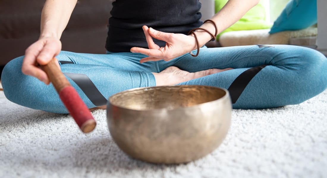 Une femme assise en position du lotus qui médite avec un Bol Tibétain