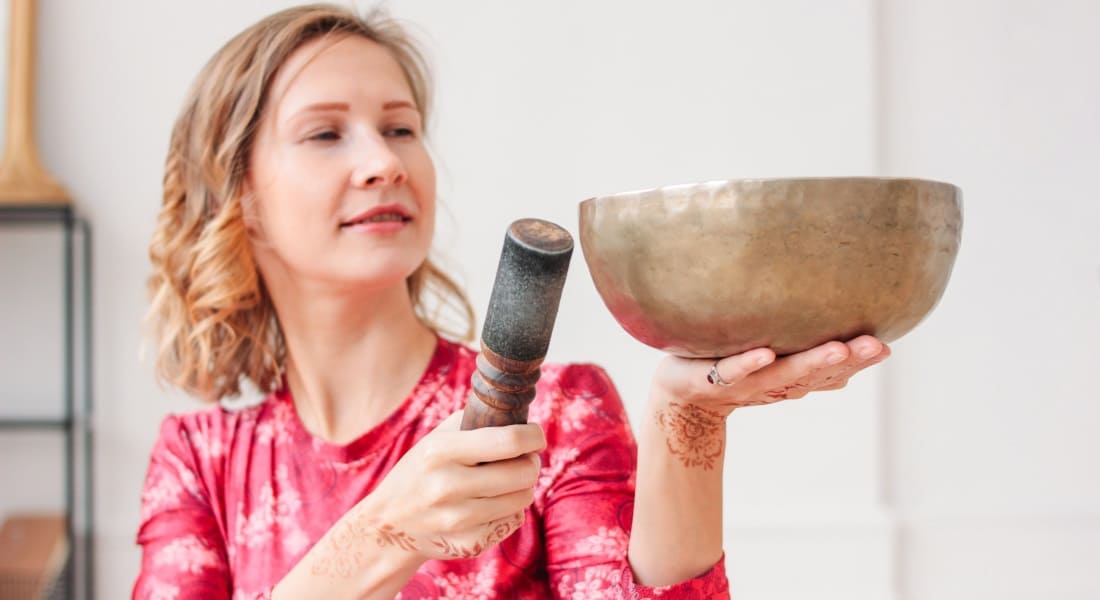 Une femme avec une robe rose et un Bol Tibétain