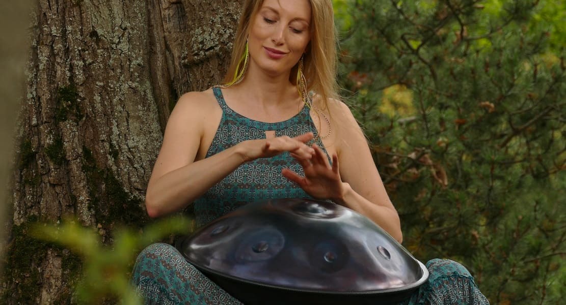 Une femme dans la forêt jouant du Handpan