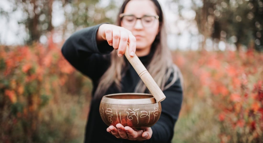 Une femme qui fait sonner un Bol Chantant avec un bâton