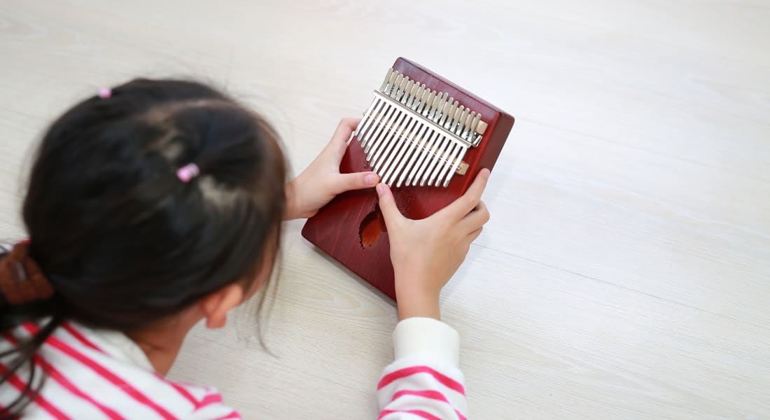 Une fille de dos qui joue du Kalimba allongée