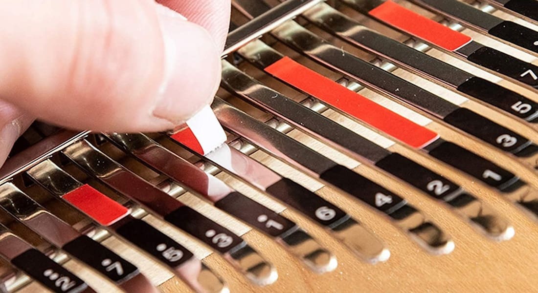 Une main qui pose des autocollants sur un Kalimba