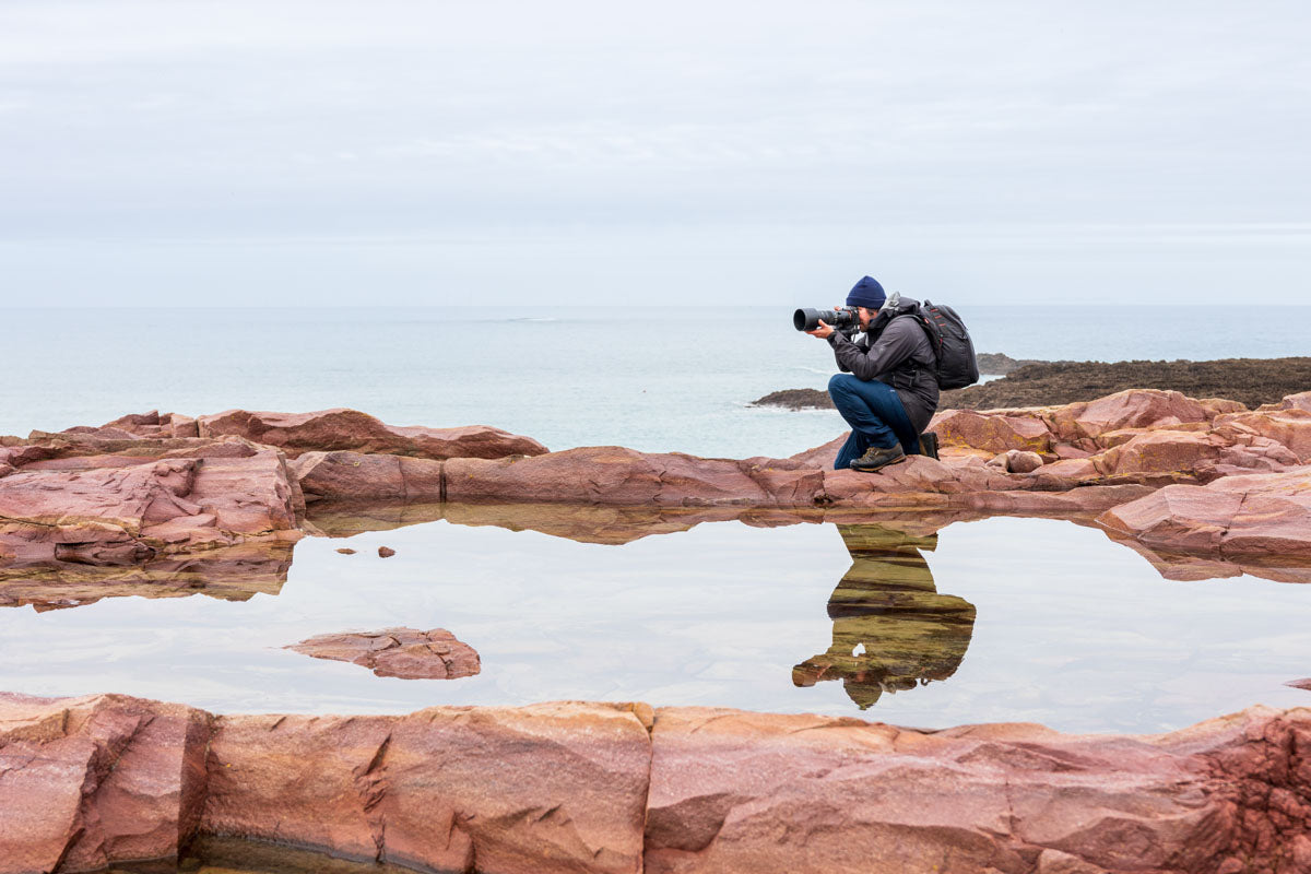 Photo of a photographer on the rocks by the beach
