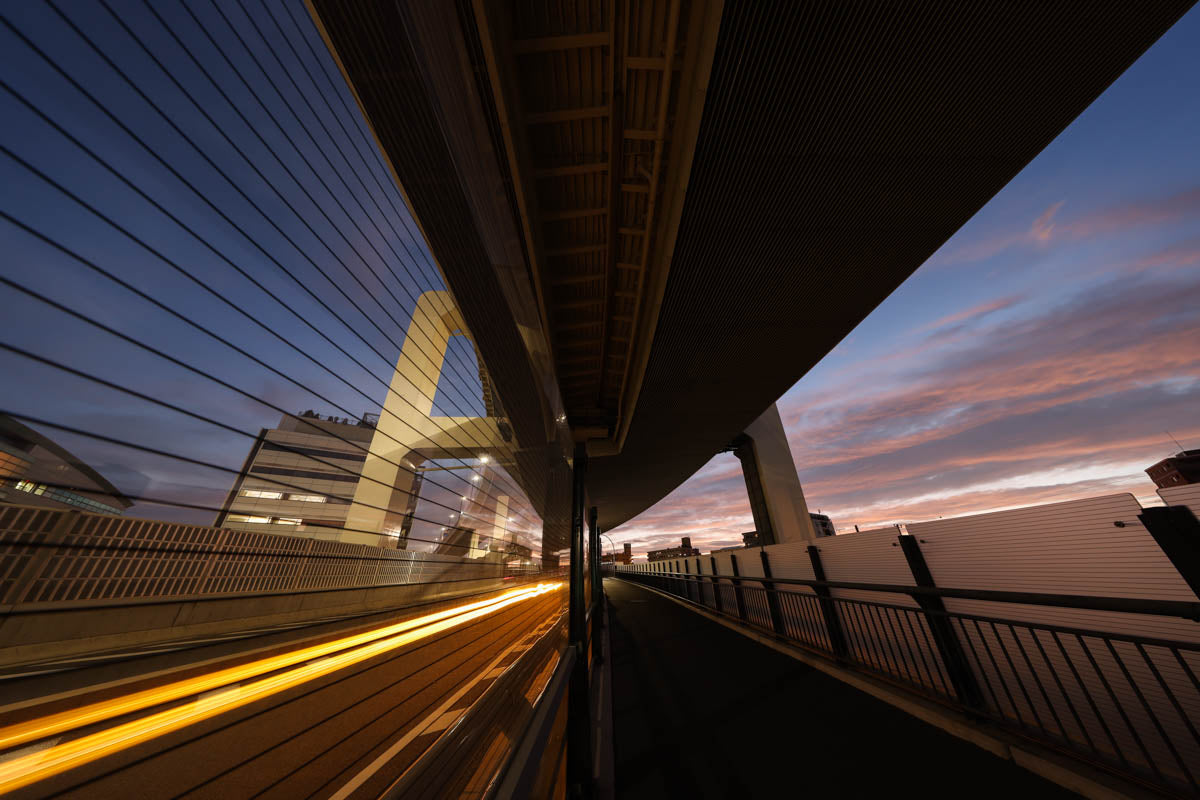 Street photography with traffic light trails under a bridge at dusk