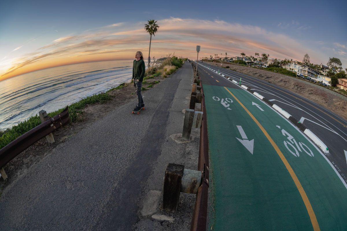 Sample photo taken on the Sigma 15mm f1.4 - Photo of a skateboarder riding along the coastline at sunset