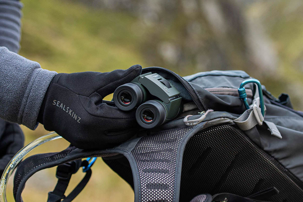 Photo of the binoculars being put into a hiking backpack