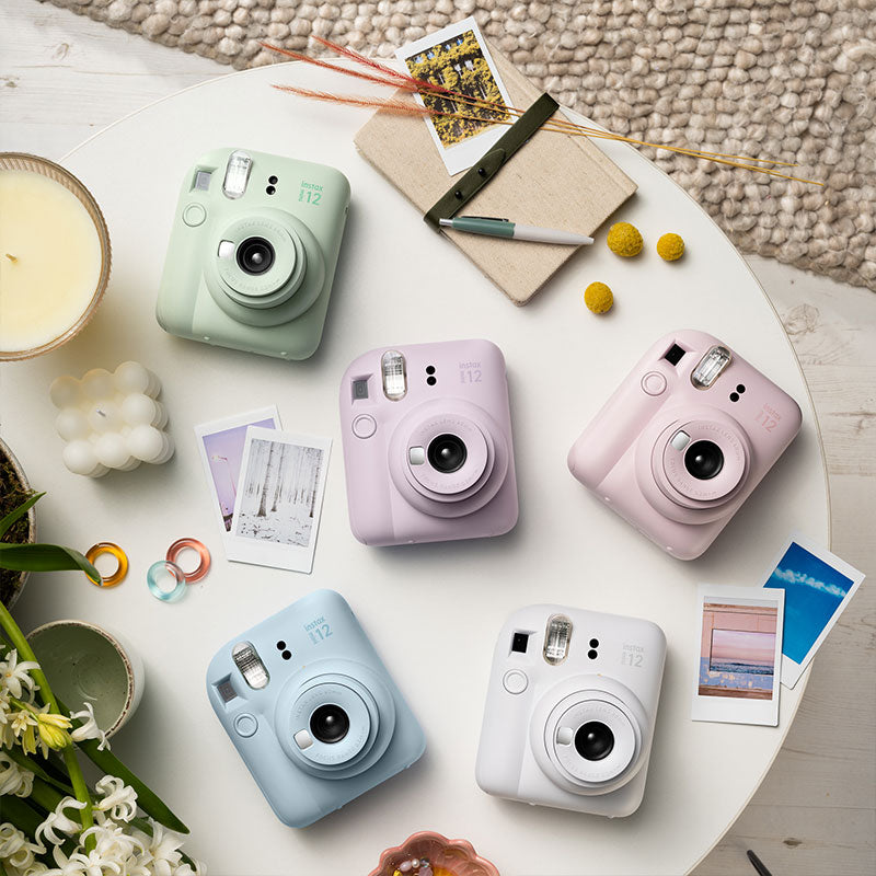 Lifestyle image of the Instax Mini 12 showing all of the products on a nice table-top background