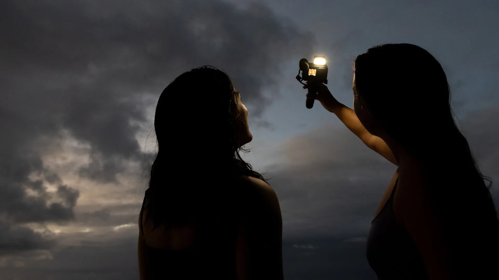 Photo of two people doing a vlogging selphie with the flash / light on