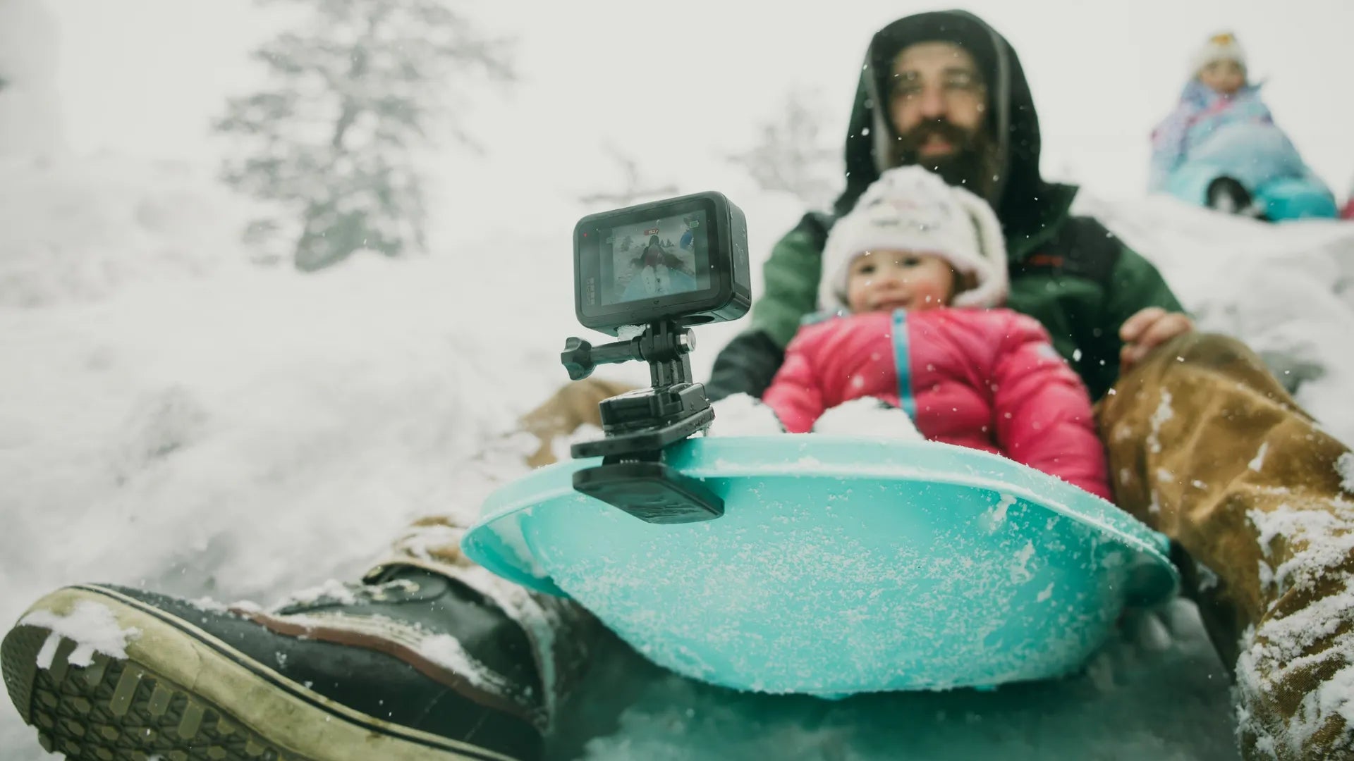 Photo of a father and son in a sledge riding down a snowy hill with the gopro camera clip attached