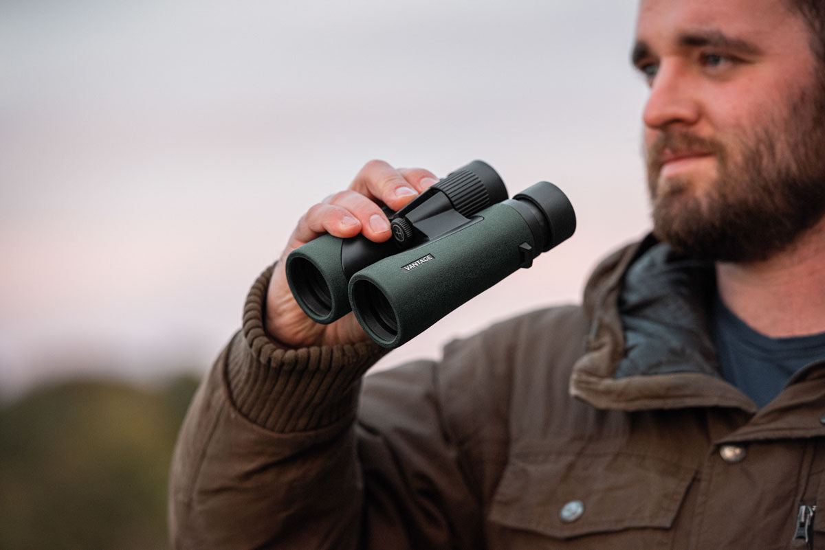 Hawke Vantage Binoculars - Lifestyle Image of a man holding the binoculars out in the field