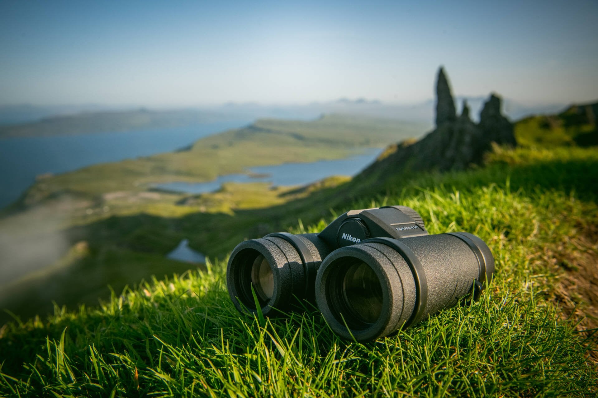 Photo of the binoculars lying on the grass in a mountainous region