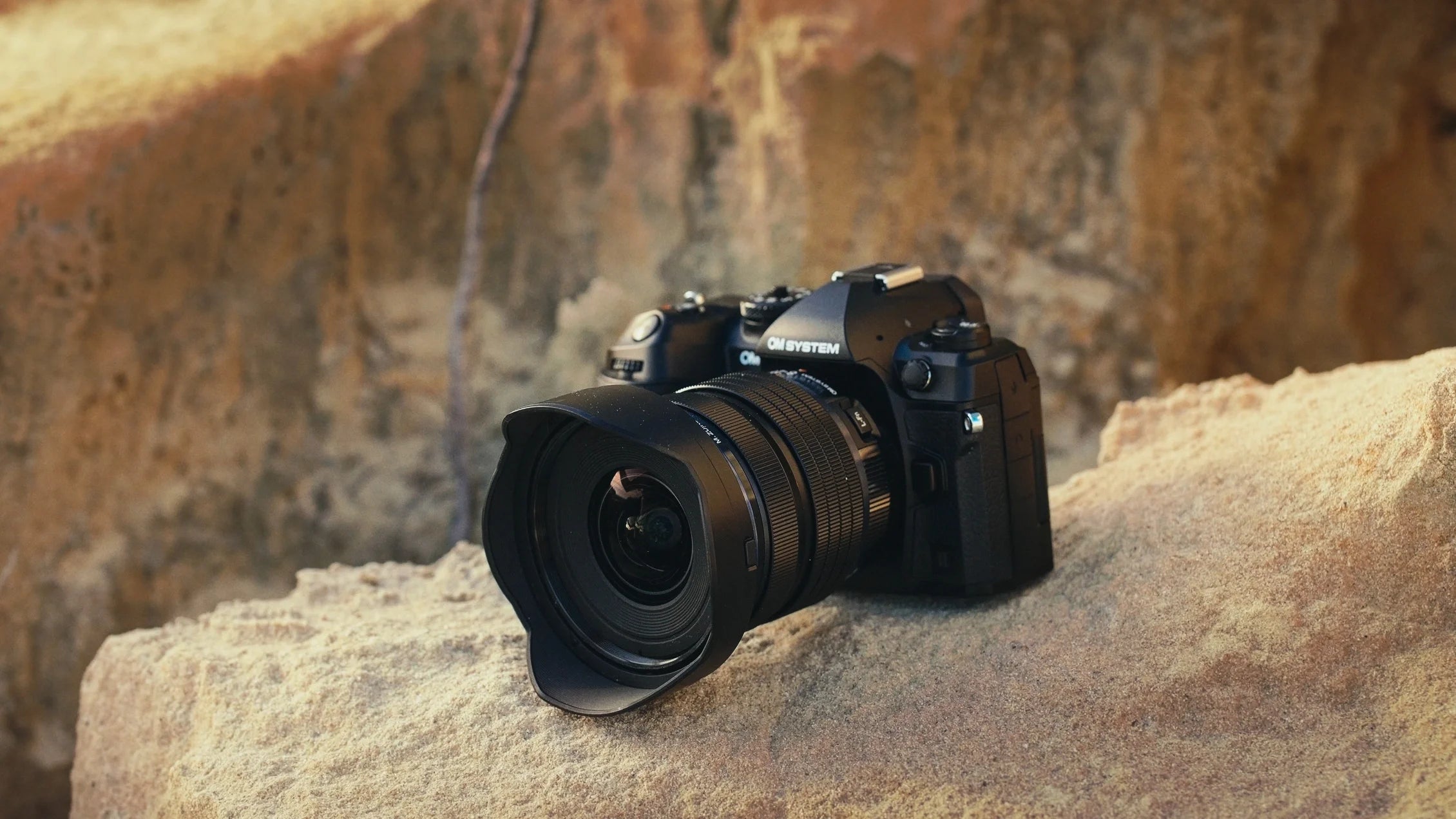 OM-1 Mark ii - Lifestyle shot of the product sitting pretty on top of a rock. That's nice