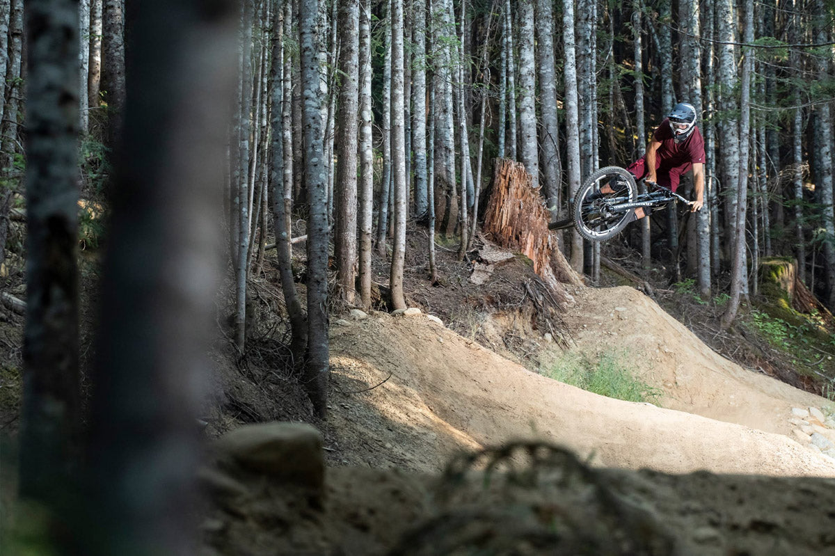 Mountain bike rider hitting a jump in the woods - Taken on the Sigma Lens