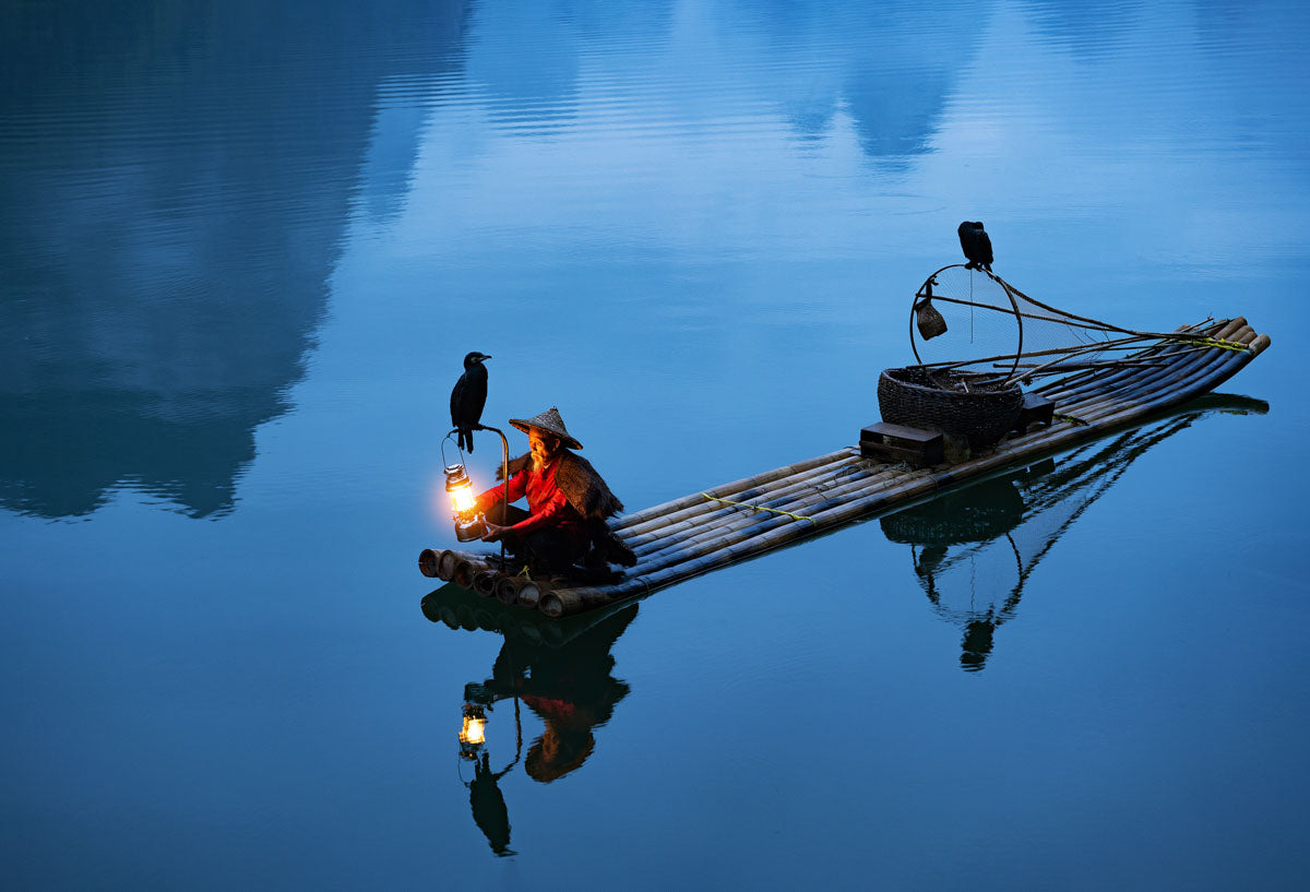 Traditional fisherman in Asia on a boat with avian hunting partner