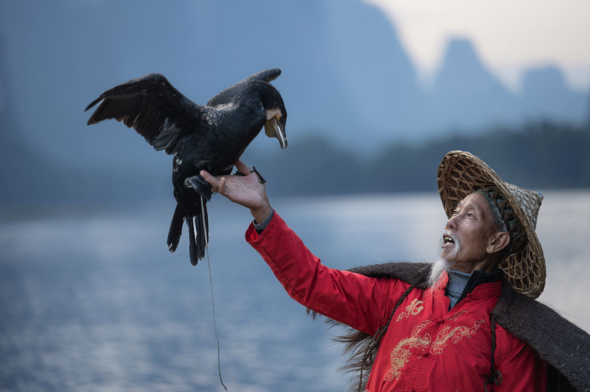 Photo of a traditional fisherman with a bird in Asia taken on the Sigma