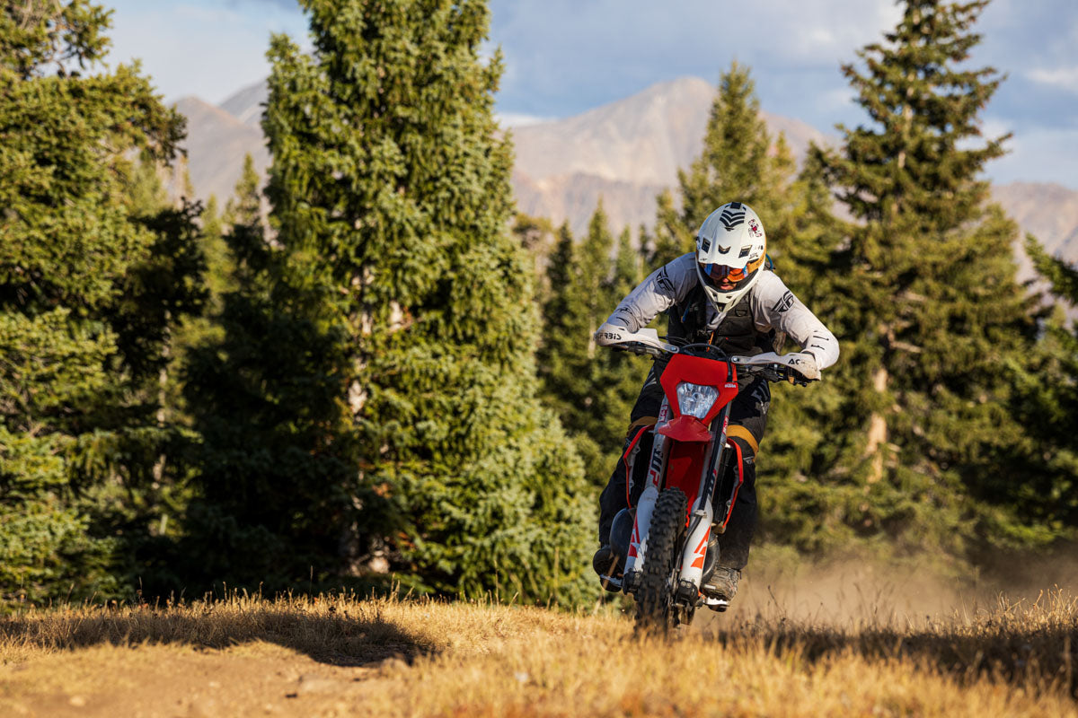 Enduro motorcycle rider in the forest and mountain in the background