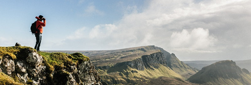 image of man standing on mountain with binoculars