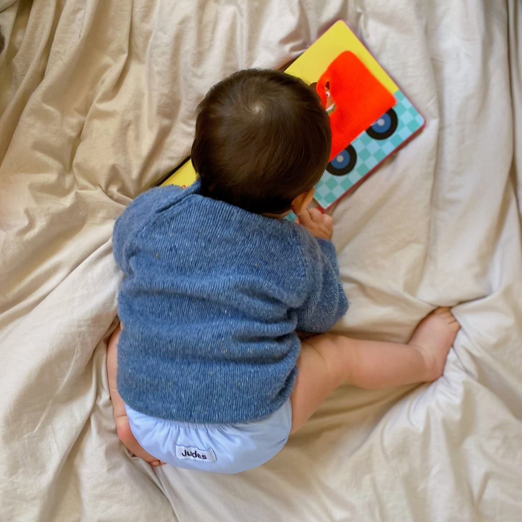 Judes Baby mit Buch auf Decke