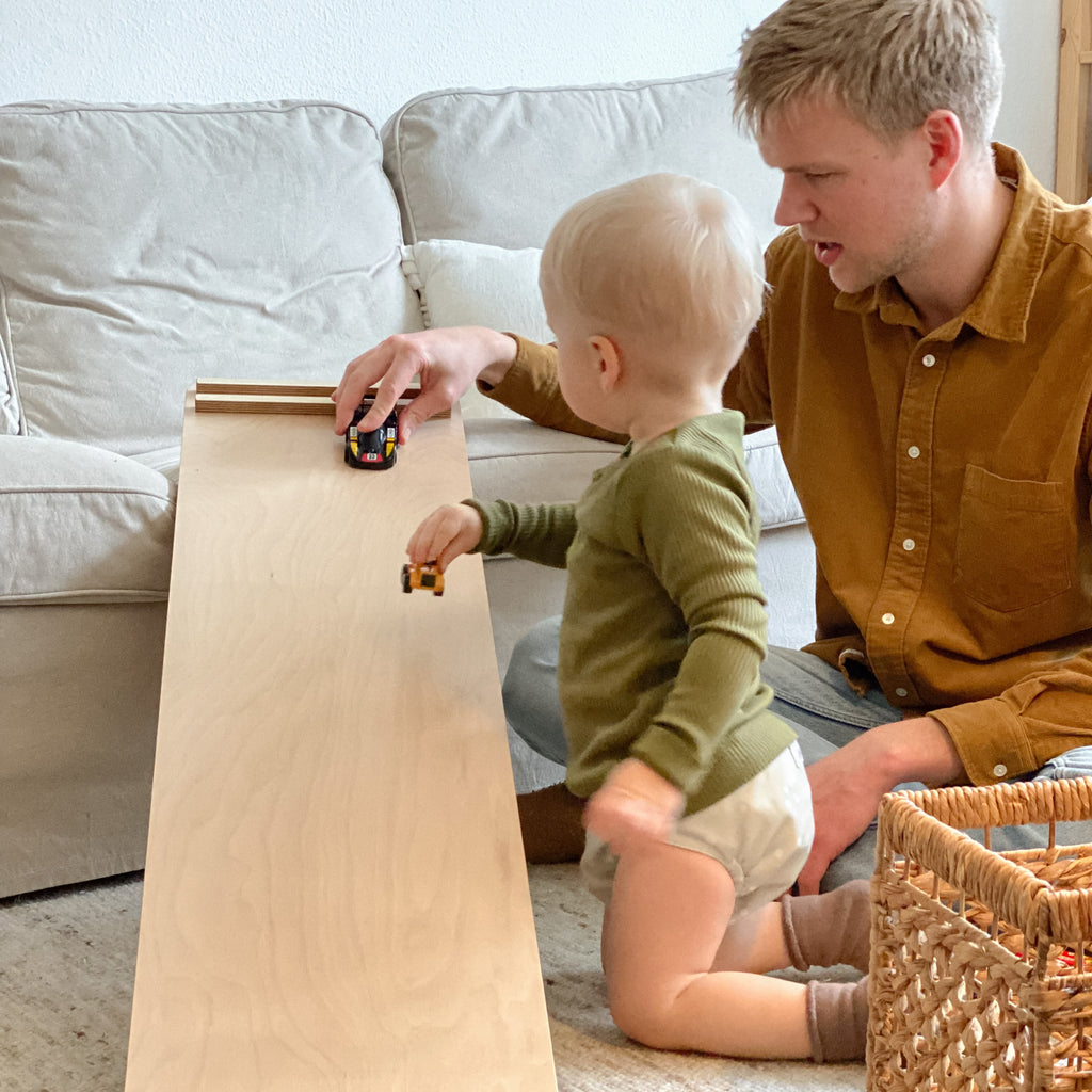 Judes Baby e papà giocano con le macchinine su una rampa di legno