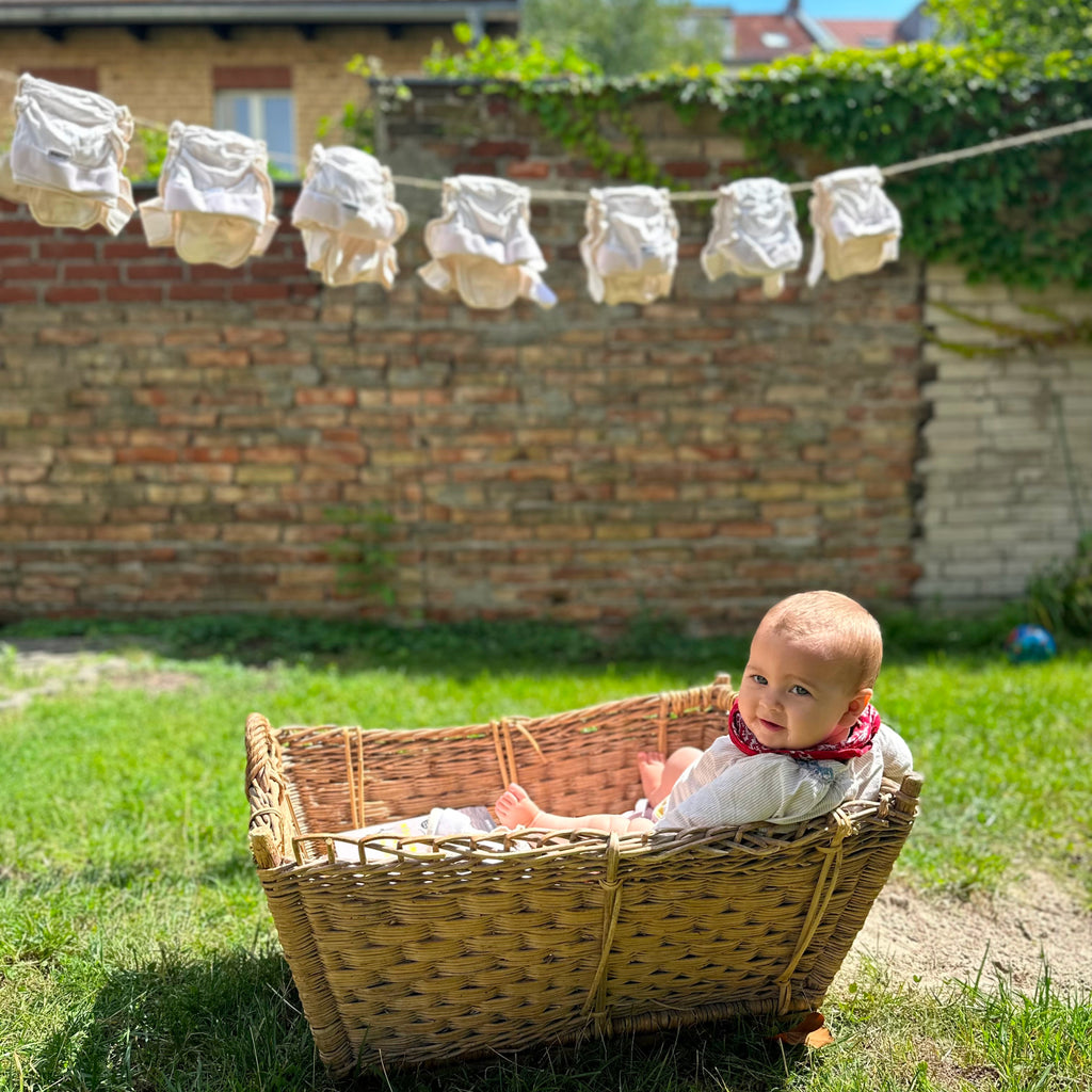 Pañales de tela Judes colgados para secar bebé sentado en canasta jardín pañales lavables
