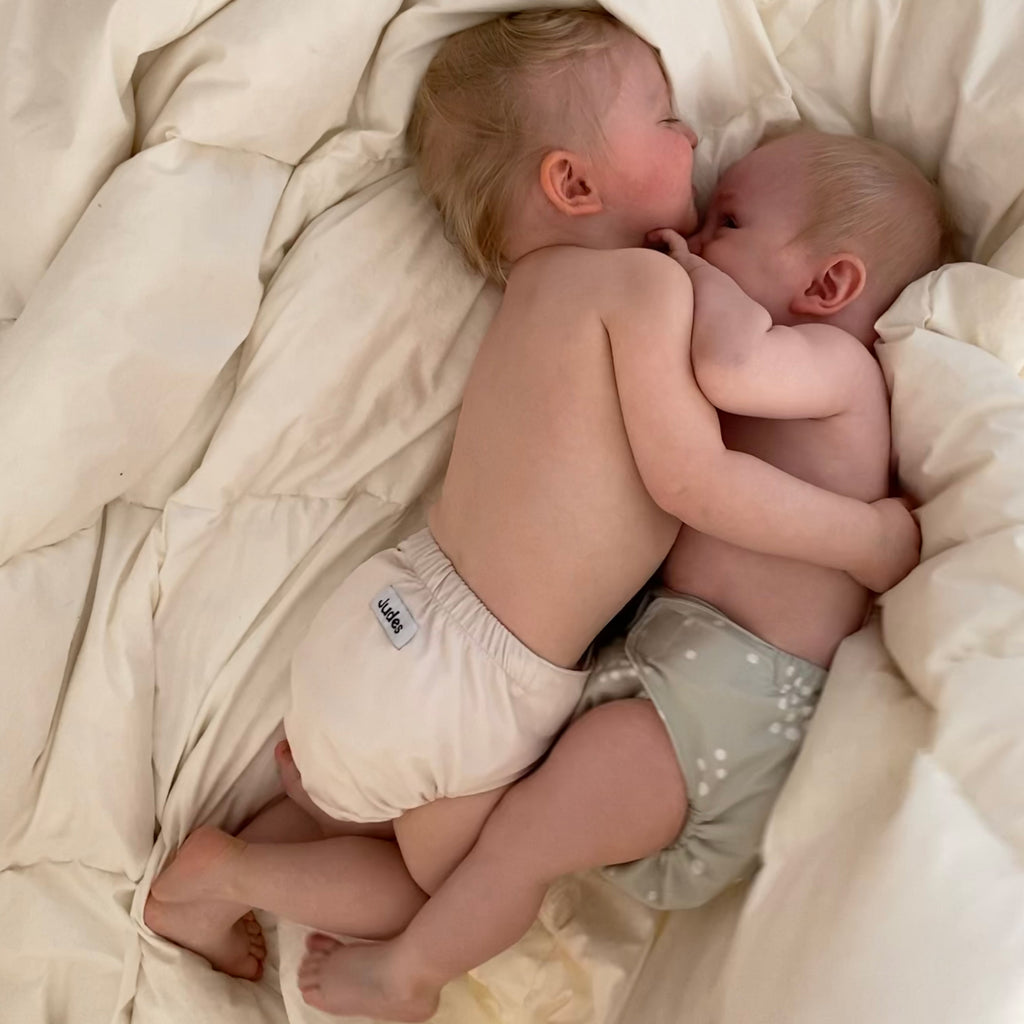 Judes due bebè si abbracciano in pannolini di stoffa su una coperta lavaggio pannolini di stoffa