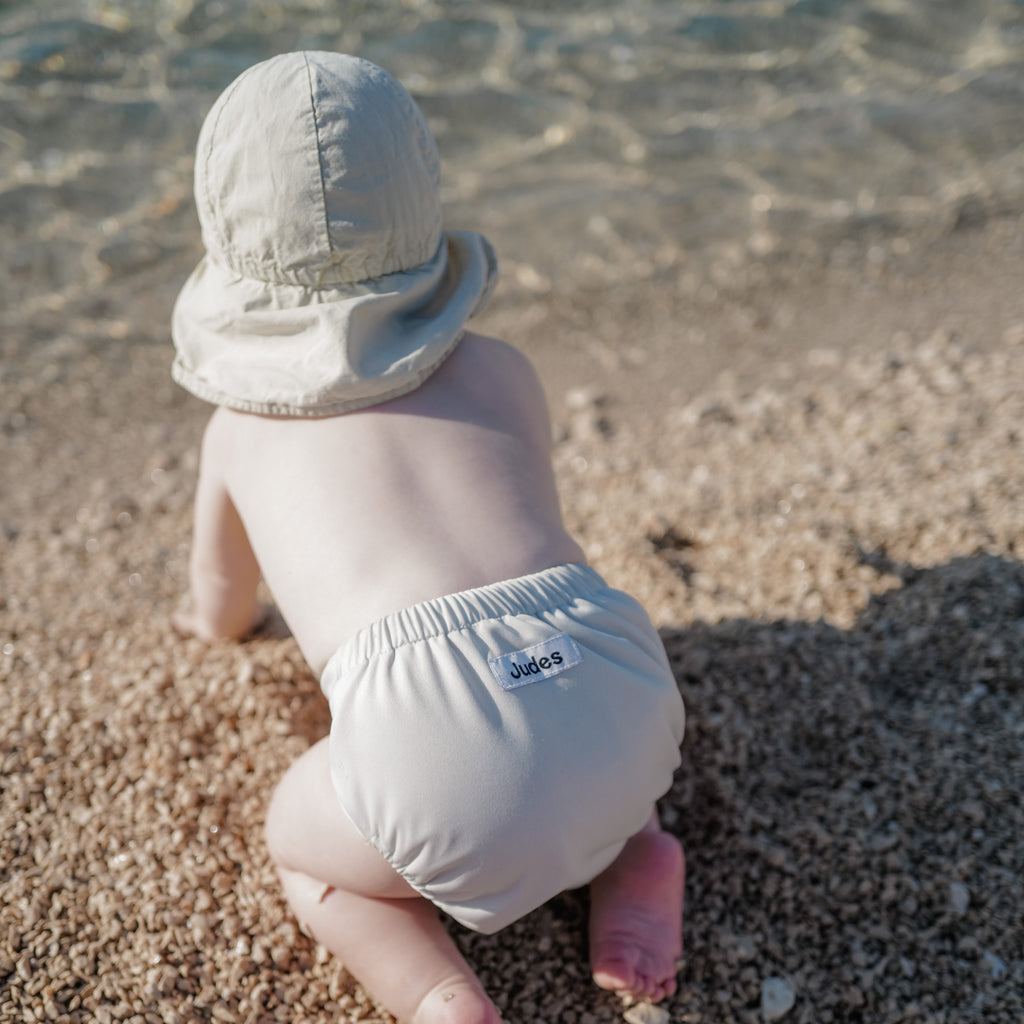 Bebé de Judes en la playa mar pañales de tela sol