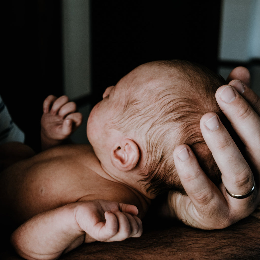 Judes Il neonato riposa tra le mani del padre.