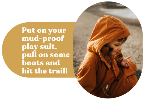Image of a young child in a rust colored waterproof playsuit sitting outside in the mud. Next to him there is text that reads "Put on your mud-proof play suit, pull on some boots and hit the trail!"
