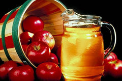 Red apples in a basket next to a pitcher of Apple cider vinegar