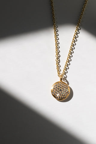 Gold pendant necklace displayed on a white table