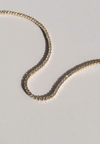 Close up of diamond tennis necklace laid out on a table
