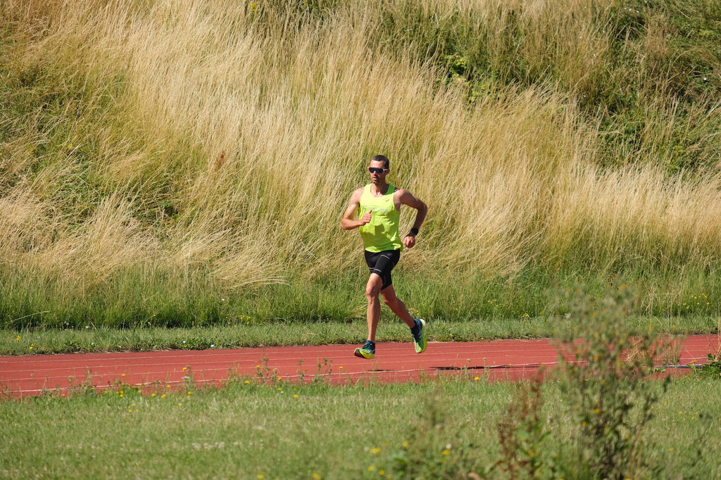 Endurance athlete running on red track.