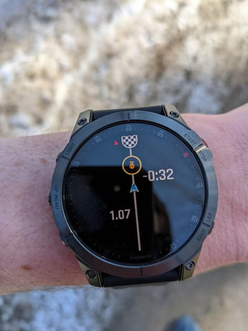 Image of a Garmin running watch on a users wrist. Strava interface is on the watch face.