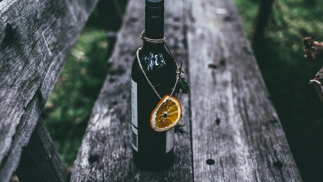 A bottle of orange wine with a dried slice of orange hanging from it
