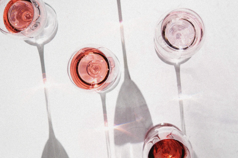 A top-down view of five wine glasses with red stains. 