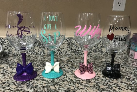 Four customized DIY vinyl wine glasses on a granite countertop.