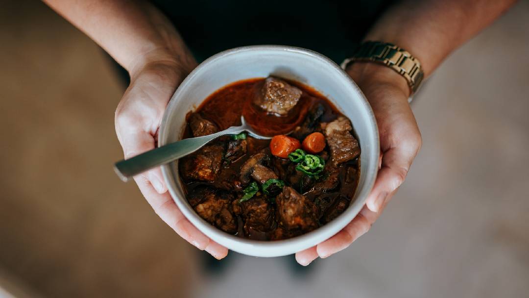  A man holding a bowl of beef stew