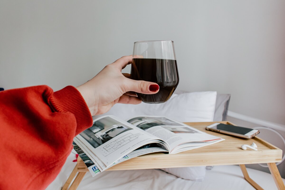 Woman holding glass of wine in bed