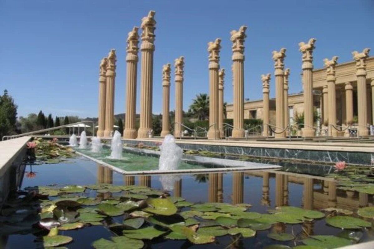 A majestic fountain with several stone pillars and lily pads.