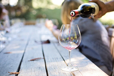 Person pouring a glass of wine at a picnic table.