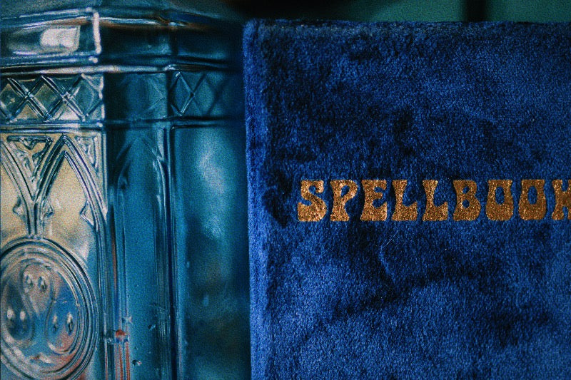 An image of a blue velvet spell book and a jar of Moonwater in a Green Witch's Home.