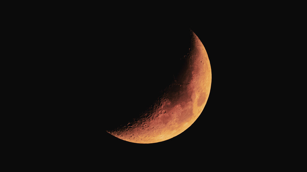 An image of the moon entering into an eclipse with the sun and changing from white to an amber-red.