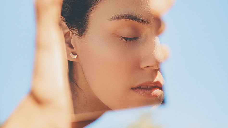 Close-up portrait of a woman symbolizing Aphrodite's beauty and grace against a serene blue background.