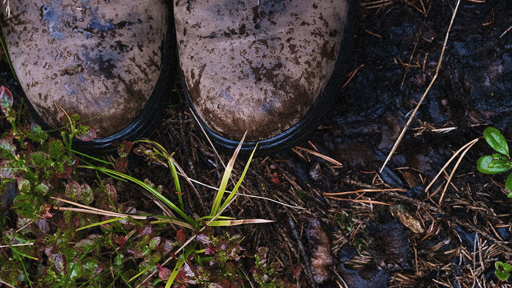 Muddy boots on a wet ground, symbolizing the grounding and preparation for change in the upcoming lunar cycle.