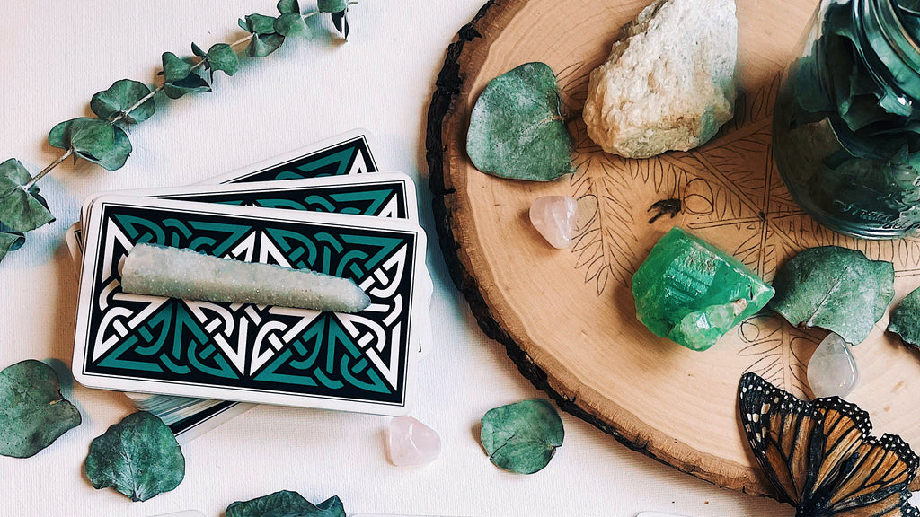 The last image depicts a tarot spread on a wooden surface surrounded by various stones and a butterfly, symbolizing transformation and change. The green stones may represent growth or healing, which can be pertinent themes when dealing with reversed tarot cards.