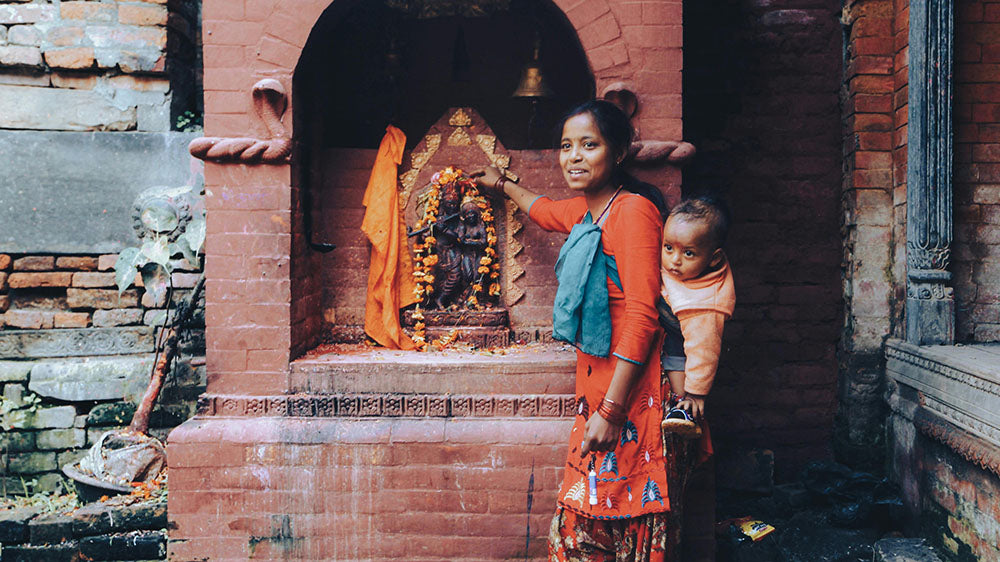 A woman and her child leaving offerings at an outdoor hindu altar