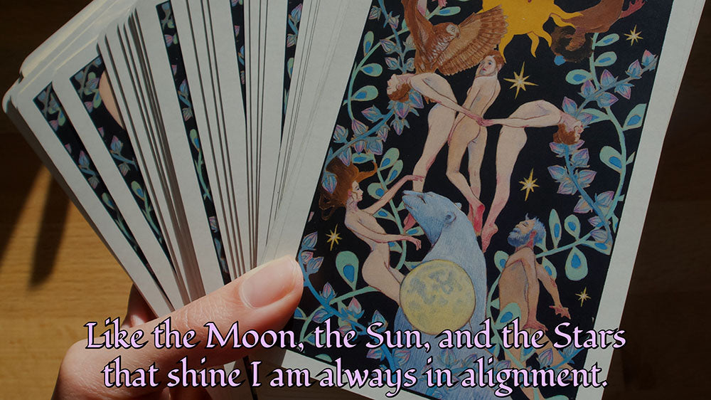 A tarot card deck being held by a person, with the text "Like the Moon, the Sun, and the Stars that shine, I am always in alignment.