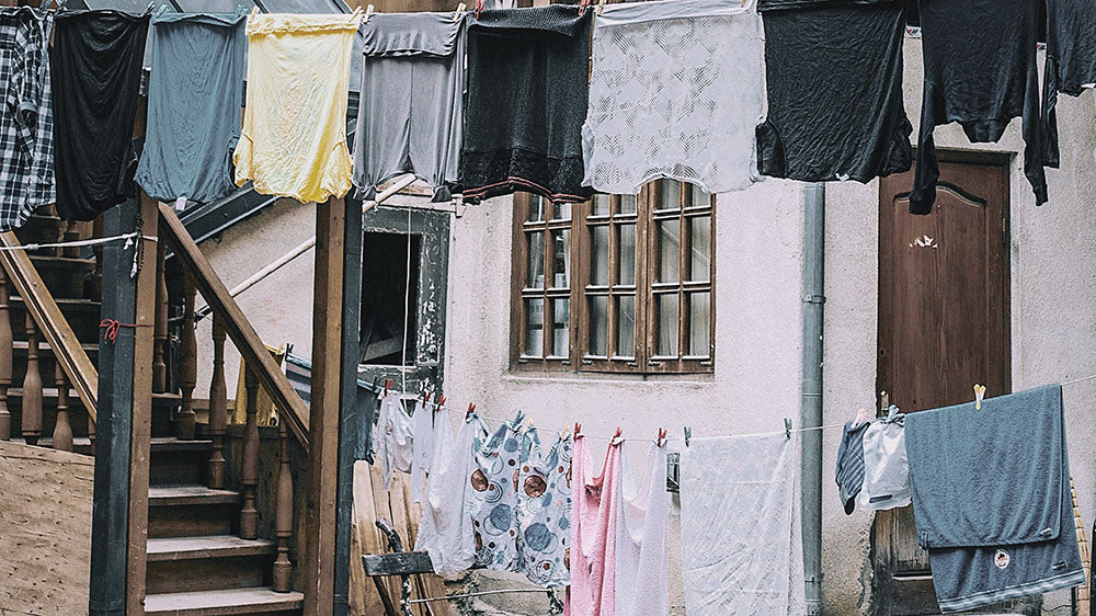 Captured in this image is a quaint scene of daily life, resonating with the grounding energy of the Mourning Moon. Lines of laundry stretch across an urban backdrop, with an array of garments in various hues drying in the open air. The assortment of clothing, swaying gently above the rustic stairway, mirrors life's simple rhythms and the Full Moon's call for reflection on the domestic front. It's a snapshot of preparation and cleansing, symbolic activities associated with the Mourning Moon, as we seek to clear the old and make way for the new.